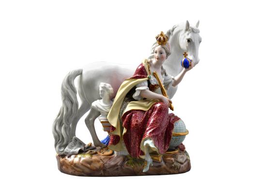 Porcelāna figūriņa ar sēdošu kronētu sievieti un baltu zirgu uz dekoratīvas pamatnes.