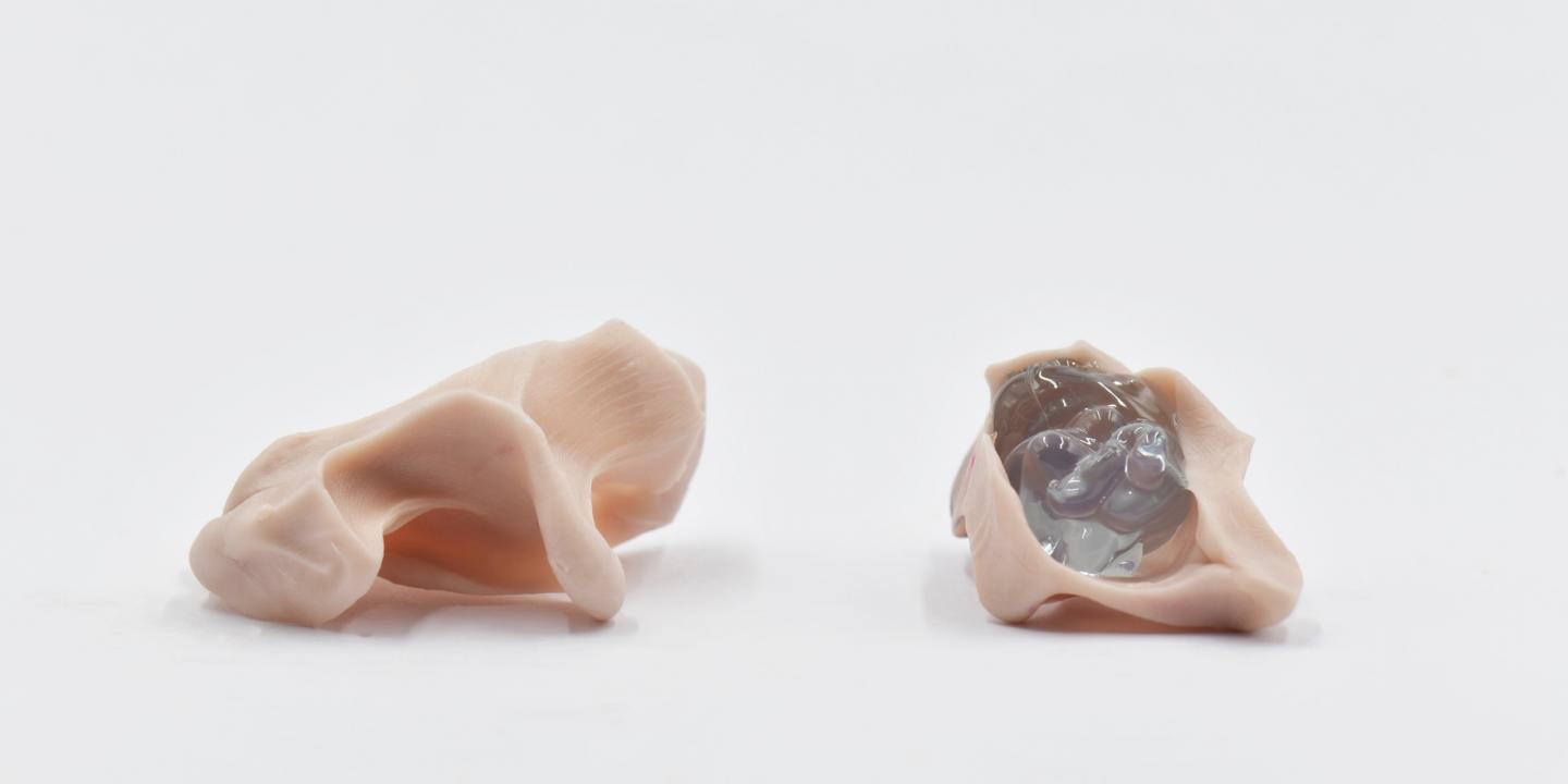 Two small pale pink and translucent sculptural objects placed on a white surface in a minimalist composition.