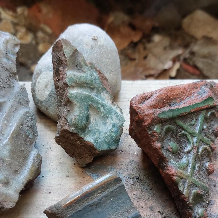 Arheoloģiski atrasti 17. gadsimta krāsns podiņu fragmenti: glazētas keramikas lauskas ar reljefiem ornamentiem un zaļganas glazūras pēdām, nolietotas un klātas ar zemes nogulsnēm.