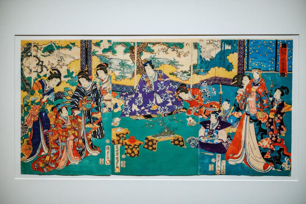 A colorful multi-panel Japanese woodblock print depicting elegantly dressed figures in an interior, displayed in a white frame.