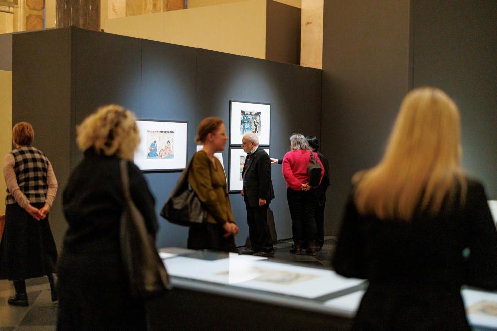 Visitors viewing Japanese prints displayed on dark exhibition panels in the museum gallery.