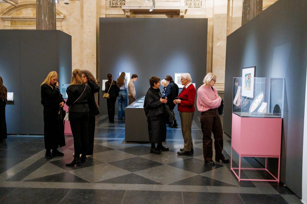 Visitors viewing Japanese artworks and objects displayed in glass cases in the museum gallery.