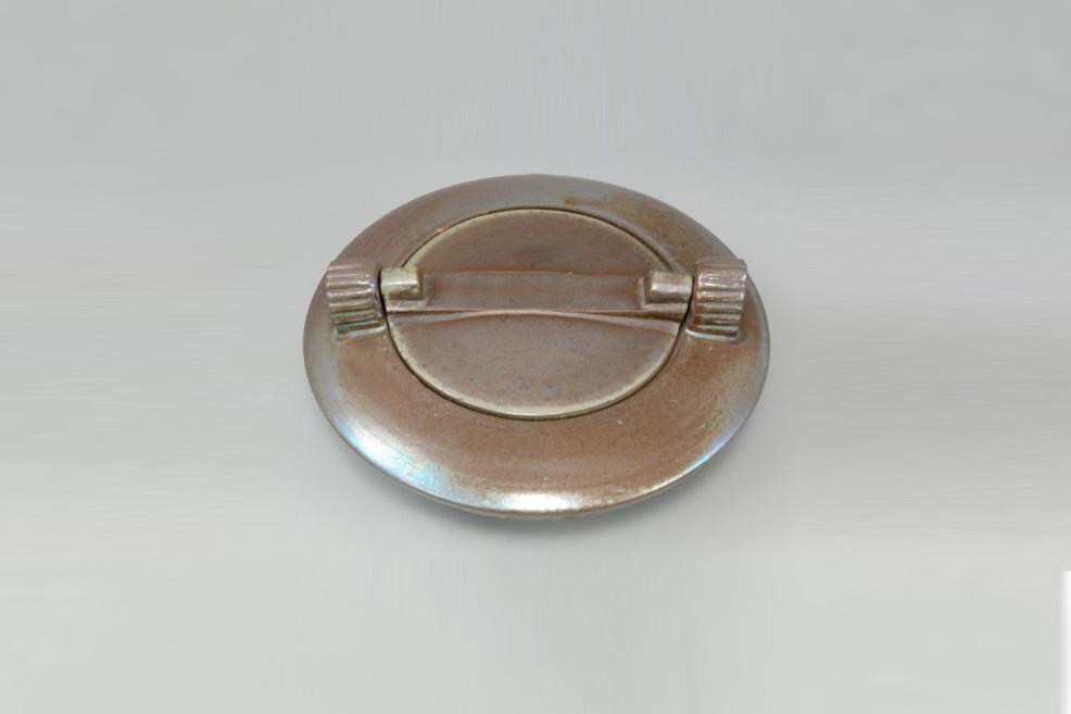 Oval bronze ashtray with a round lid and two ribbed handles on a light background.
