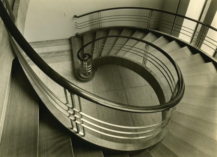 Black-and-white photograph of the elegant curved staircase in the Roche management offices in Basel.