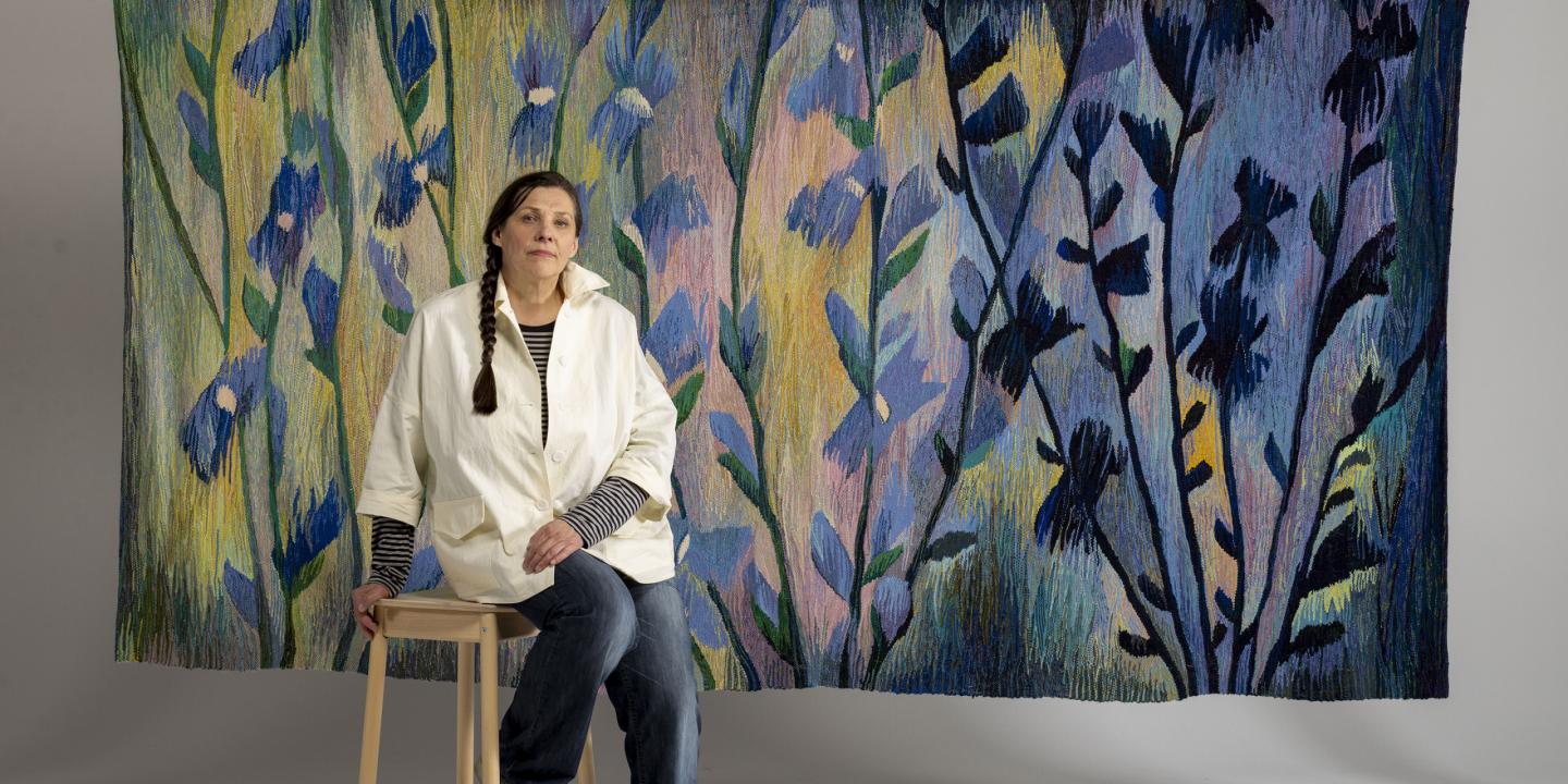 Tekstilmākslinieces Ivetas Vecenānes portrets ar gobelēnu &ldquo;Cigoriņi&rdquo; (2019). 2025. Foto: Didzis Grodzs