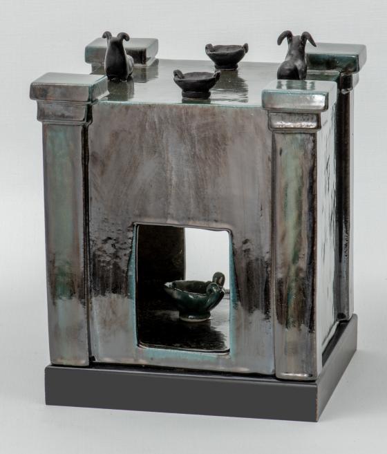 Square ceramic altar with small vessels on top and an opening in the center.