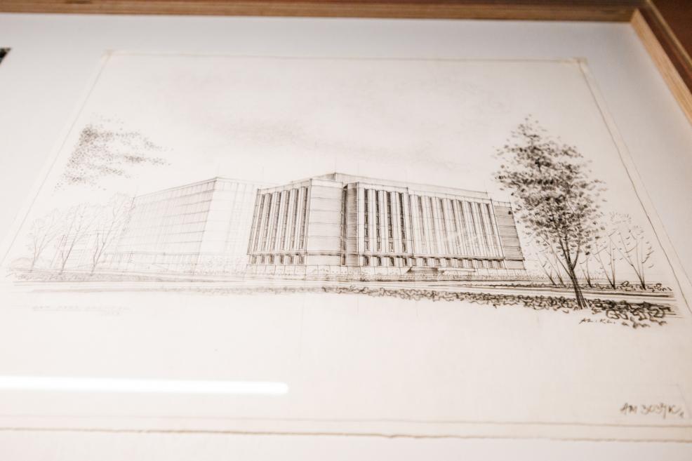 Arhitektūras zīmējums – liela apjoma ēka perspektīvā ar kokiem apkārt.