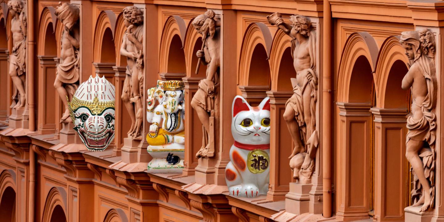 Decorative figures from different cultures are placed between classical sculptures on the museum building façade.