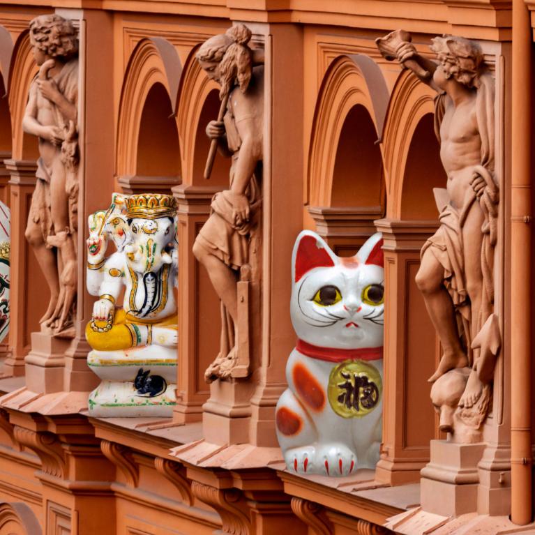 Decorative figures from different cultures are placed between classical sculptures on the museum building façade.