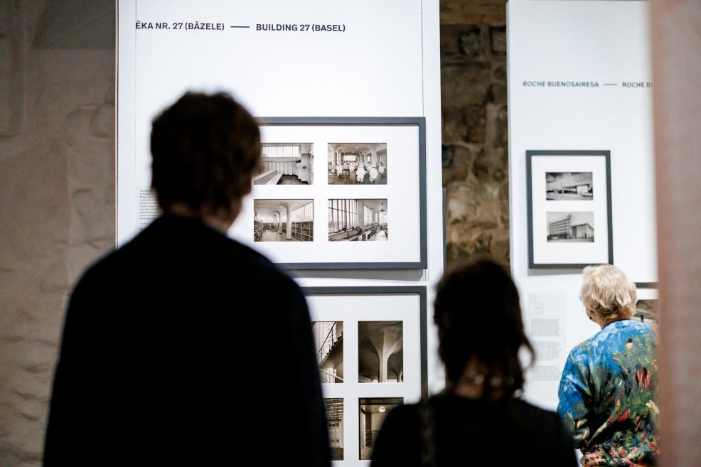 Visitors at the exhibition observe an information panel about Roche architecture.
