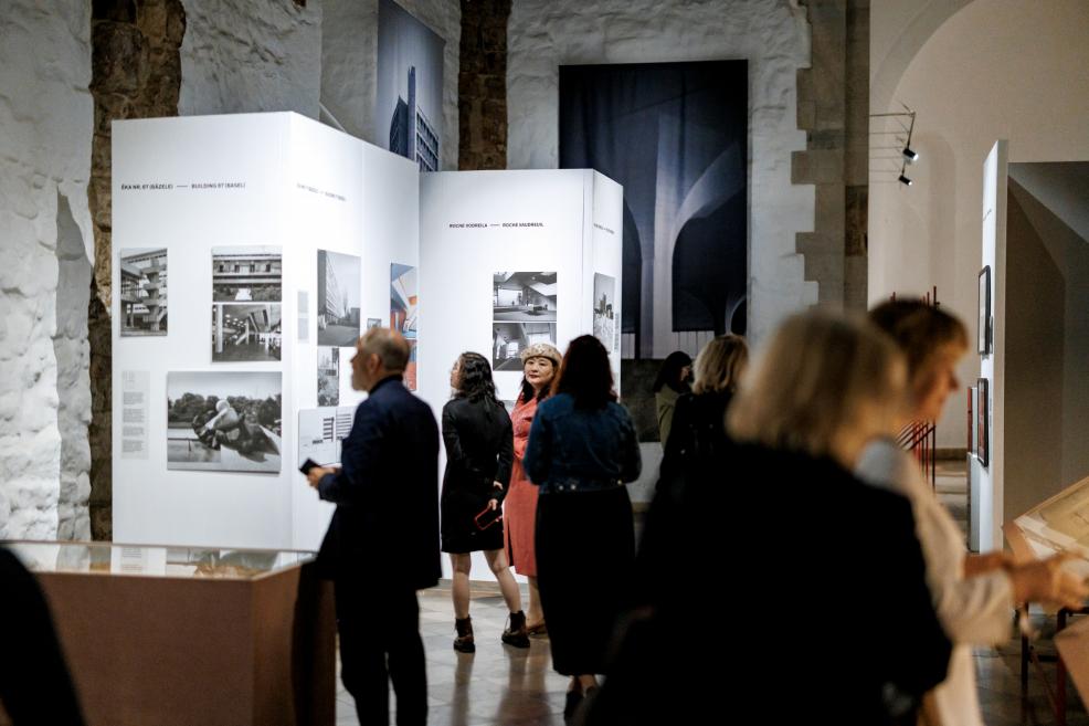 Visitors in close-up view historical photographs of a Roche building.