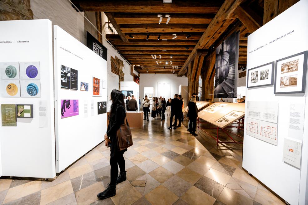 People at the exhibition look at architectural photographs and information panels.