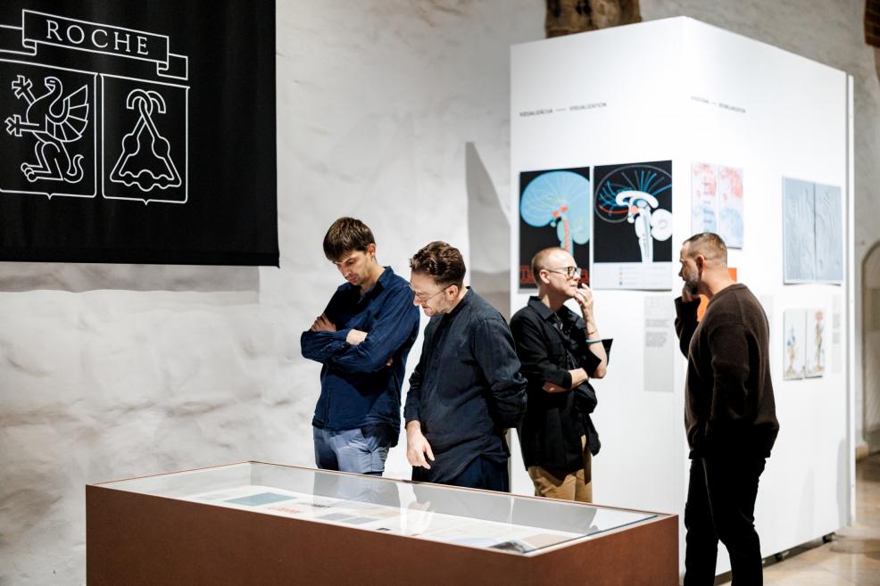 A woman views an exhibition stand with photographs and architectural materials.