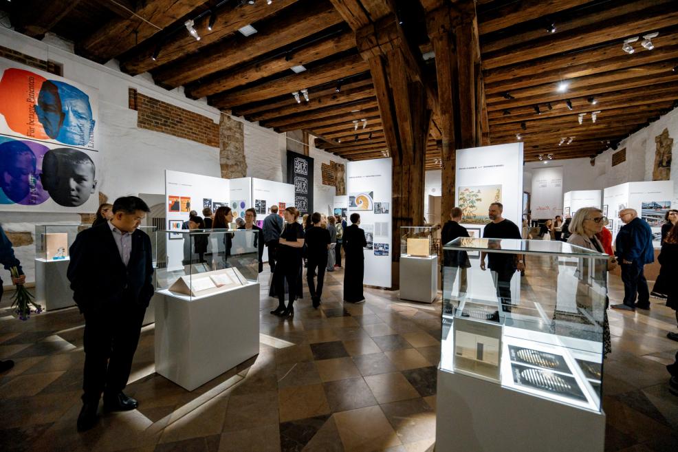 In the museum exhibition hall, visitors observe artworks and architectural displays.