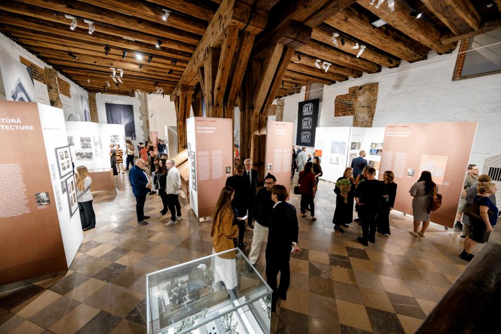 In a museum hall with wooden ceilings, visitors view the exhibition.