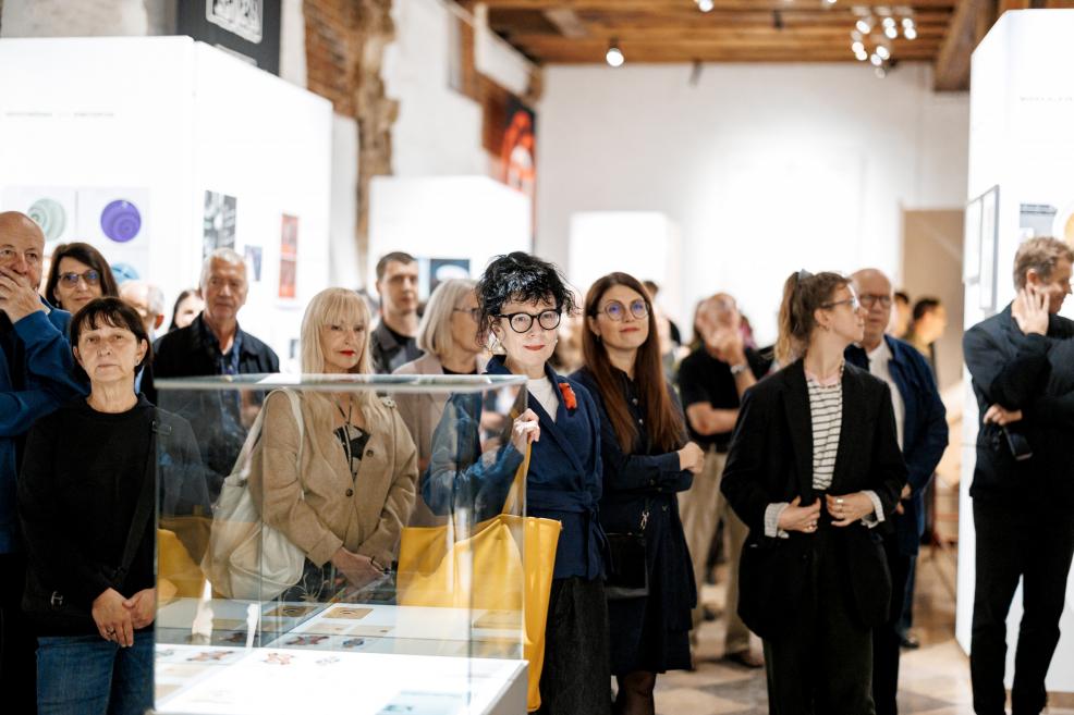 Museum visitors stand by a showcase and listen to a presentation.