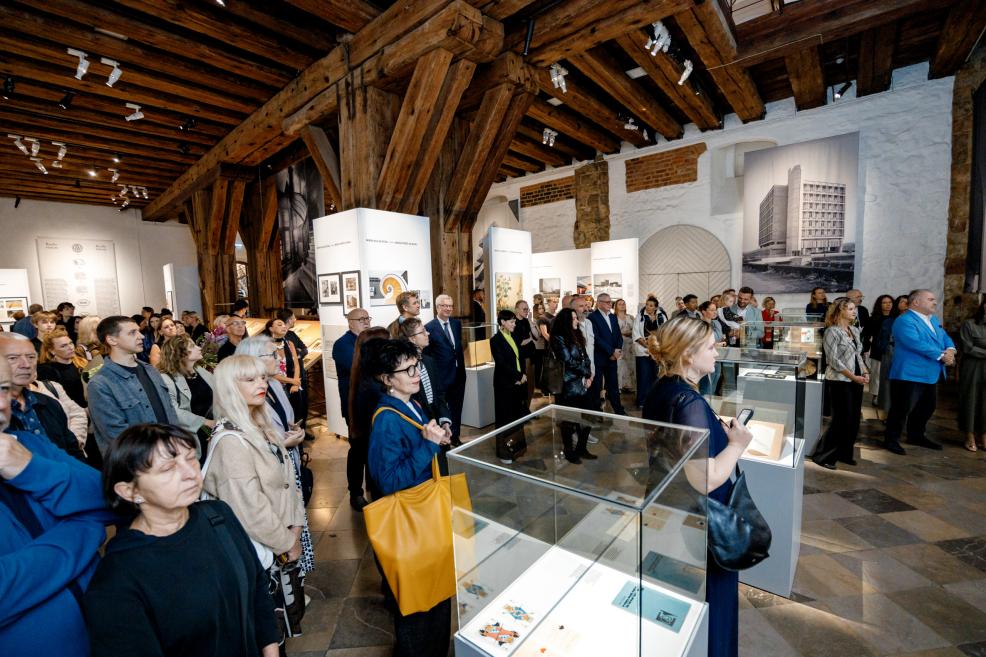 Museum visitors in the exhibition hall explore the architectural display.