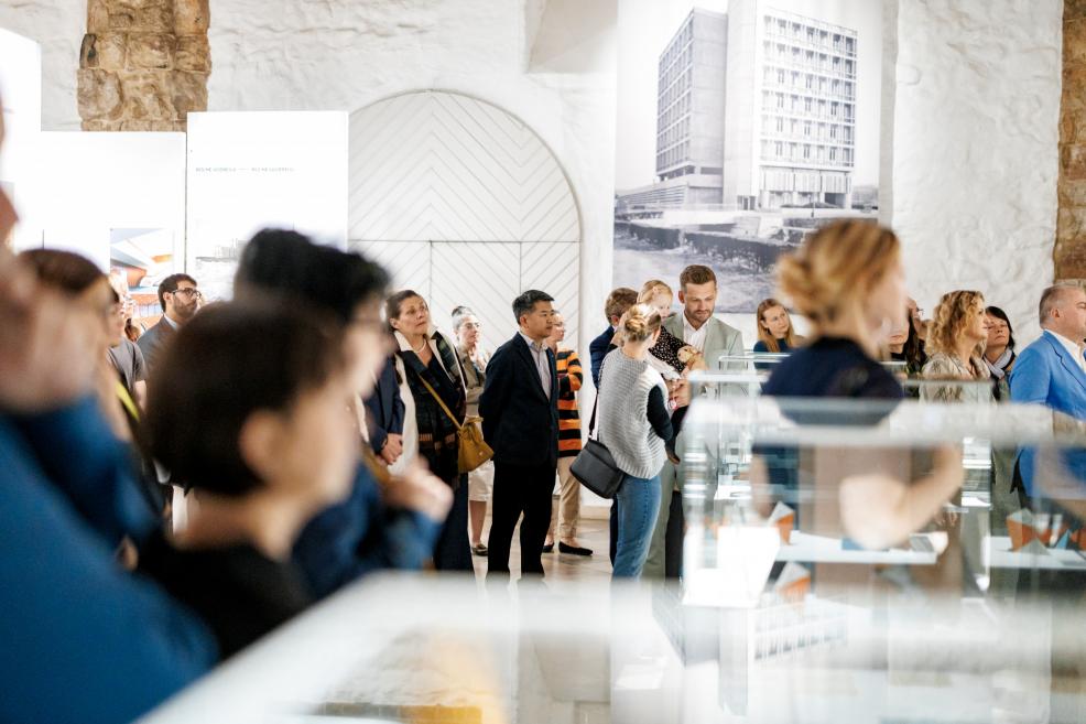 Museum visitors in the exhibition hall explore the architectural display.