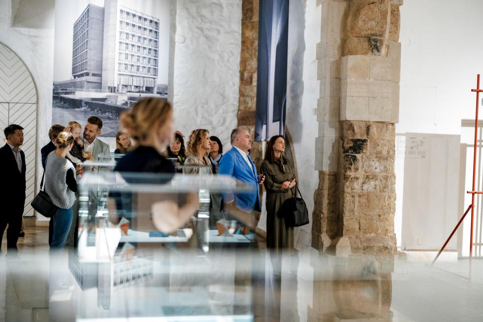 People viewing an exhibition in a museum next to display cases with artworks.