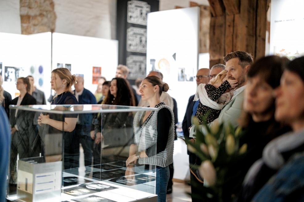 Visitors observing the exhibition near glass display cases.
