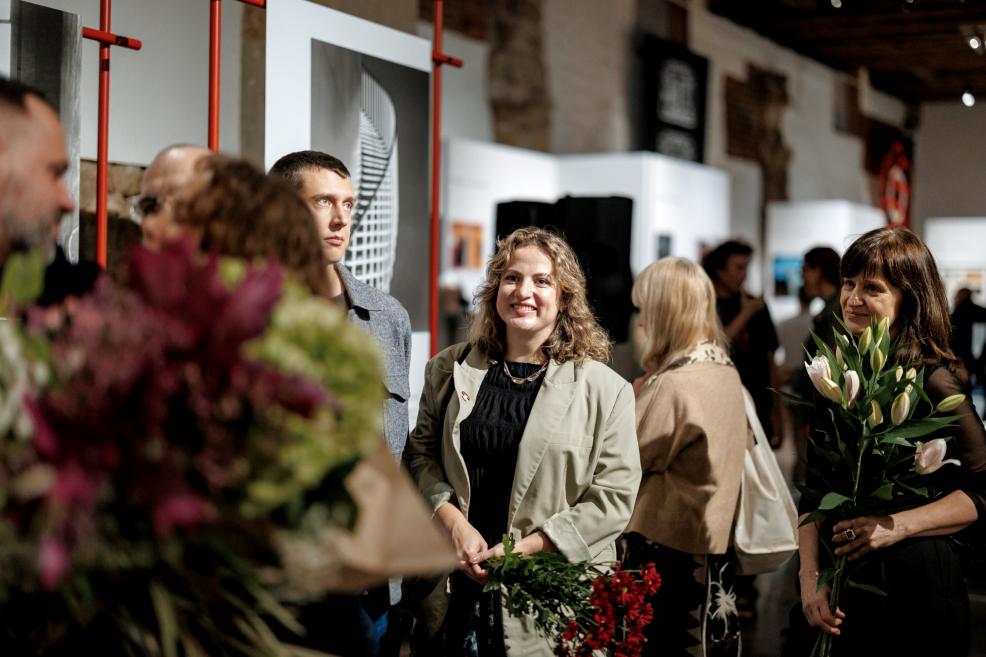 Exhibition visitors holding flowers at the opening event.