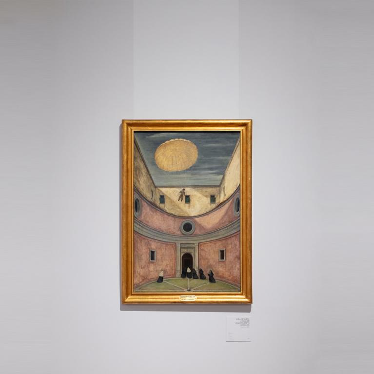 Glezna zelta rāmī pie baltas izstāžu zāles sienas; attēlots arhitektūras pagalms ar skatu uz augšu, kur debesīs redzams krītošs cilvēks ar izpletni, bet apakšā stāv melnos tērpos tērptas figūras.