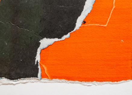 Tuvplāna fragments ar plēstas faktūras papīra gabaliem spilgti oranžā un tumši pelēkā tonī, pārklājoties uz balta fona.