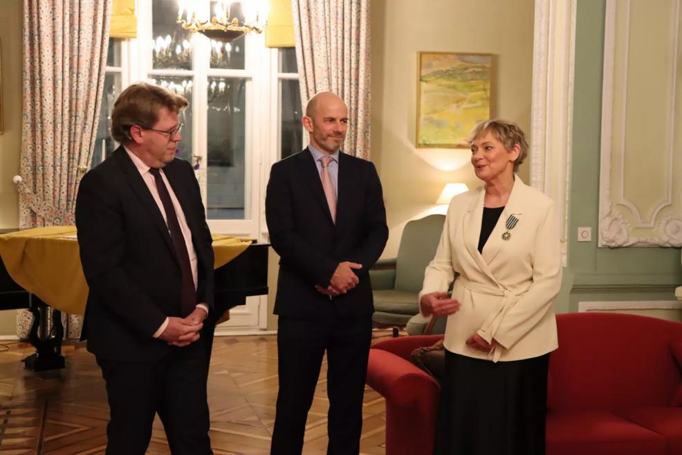 Three people at an official reception in a formal interior, one person addressing those present.