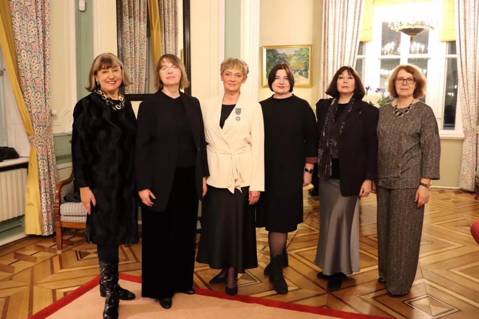 Grupas portrets formālā pasākumā reprezentatīvā interjerā, kur piecas personas pozē kamerai.