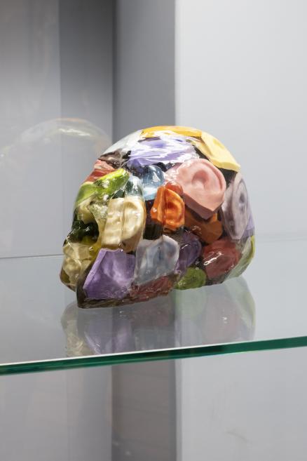 Colorful translucent skull-shaped sculpture in a museum display case.