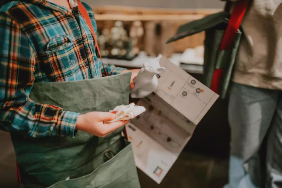 Zēns tur karti un baltu kaķa figūru, pētot ekspozīcijas telpu.