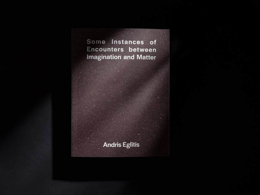 Uz melna fona novietots grāmatas “Some Instances of Encounters between Imagination and Matter” vāks ar autora vārdu Andris Eglītis.