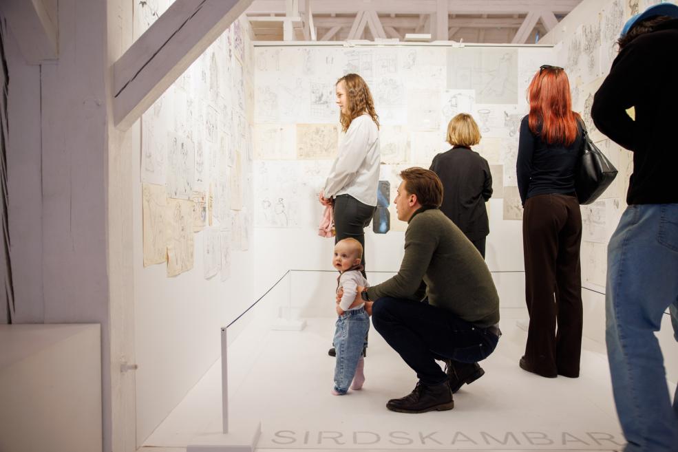 Exhibition visitors view the works.